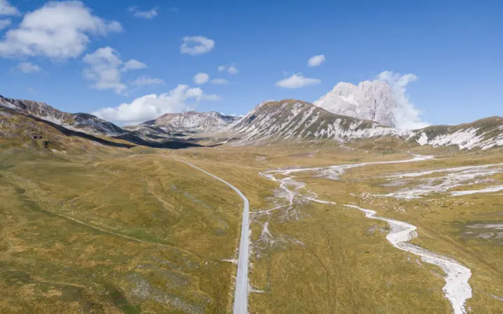 Krajobraz s planinama i kanjonom pod oblačnim nebom u talijanskom prirodnom okruženju.