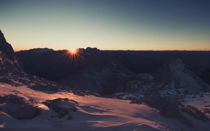 Planina pod plavim nebom sa suncem i oblacima u prvom planu za doživljaj avanture.