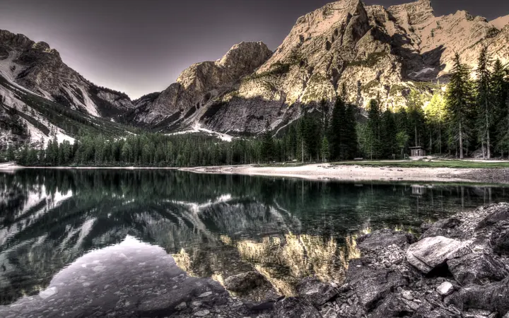 Jezero uz planine Dolomite s jasnim nebom i prirodnim zelenim okruženjem.