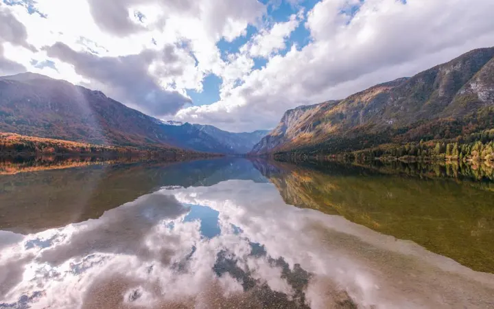 Jezero okruženo planinama ispod oblaka s prirodnim dnevnim svjetlom i mirnim ugođajem.