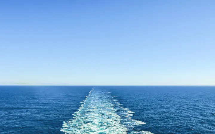 Plava morska površina s nautičkim elementima i vidljivim horizontom u pokretu.