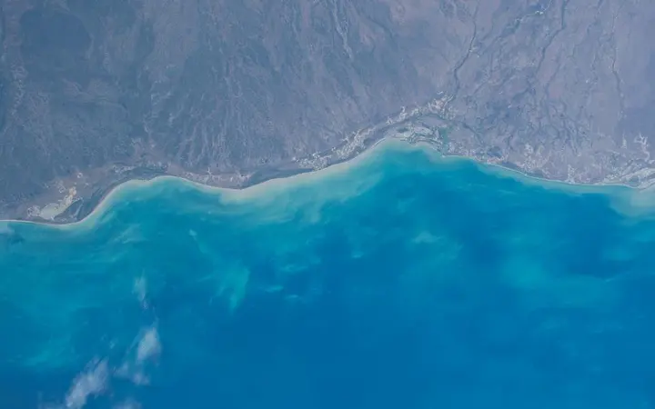Široki pogled na ocean i planine uz obalu pod vedrim nebom.