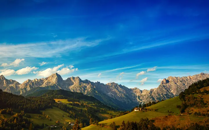 Livada na planini s plavim nebom i dramatičnim zelenim brežuljcima.