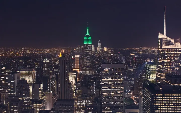 Tamni gradski pejzaž New Yorka s visokim zgradama i svjetlima u večernjim satima.
