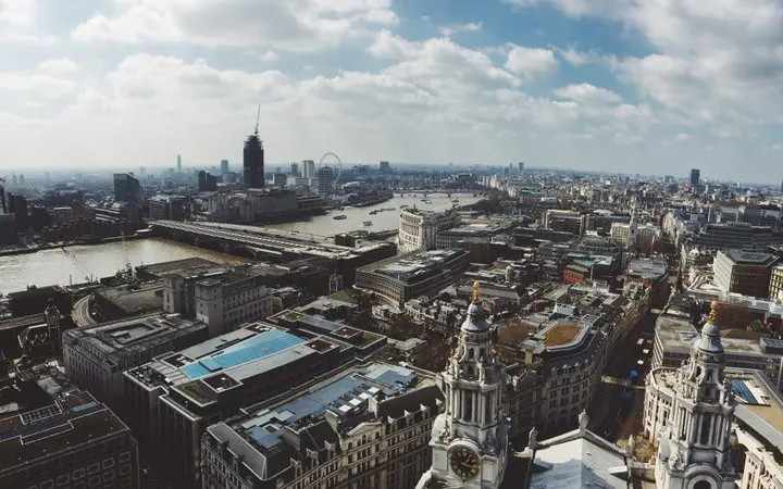 Pogled iz zraka na gustu mrežu zgrada u Londonu pod oblacima uz vedro svjetlo.
