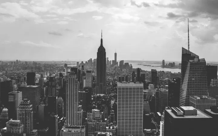 Monokromatski prikaz gradskih zgrada i oblaka u panorami New Yorka.