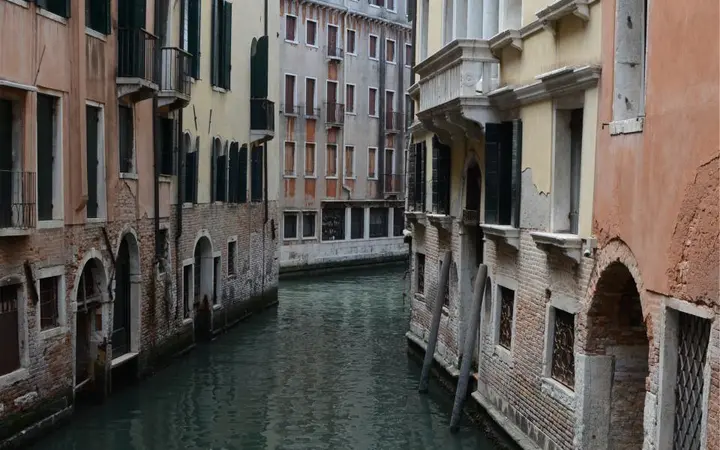 Stare zgrade uz uske kanale u Veneciji s toplim dnevnim svjetlom.
