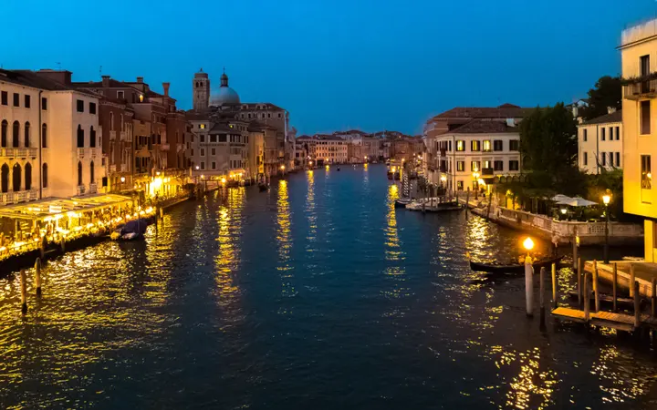 Osvijetljeni kanali i zgrade u Veneciji stvaraju romantičnu večernju atmosferu.