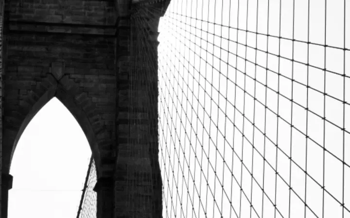 Crno-bijeli prikaz kabela i arhitekture Brooklynskog mosta u američkom gradu.