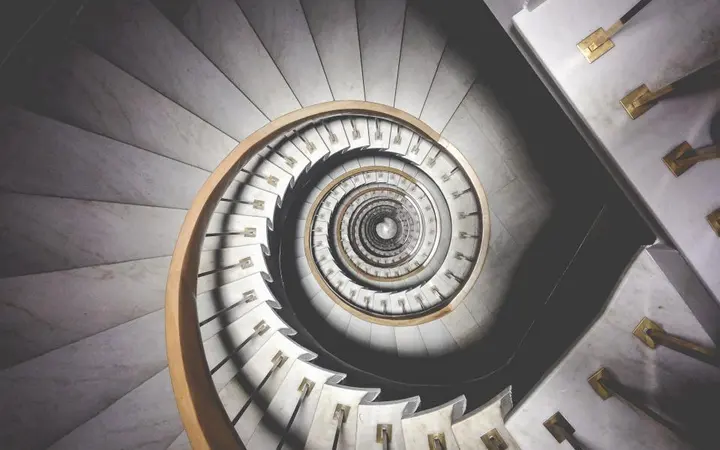 Spiralne stepenice s metalnom ogradom u industrijskom stilu s hladnim tonovima i jasnim linijama.