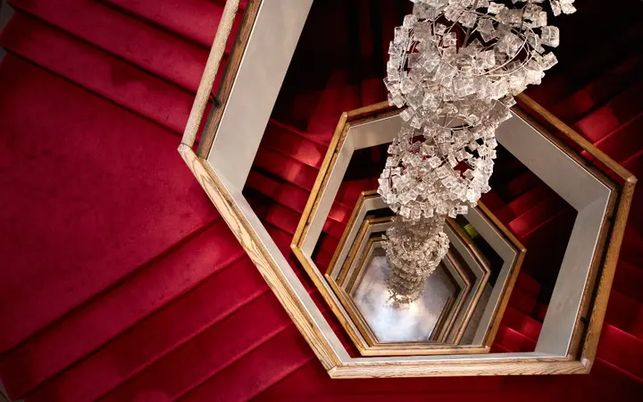 Spiralne stepenice s klasičnim tepihom u elegantnom prostoru s naglaskom na detalje i dizajn.