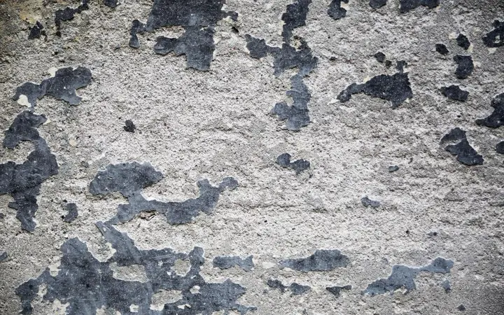 Gruba betonska površina zida s nepravilnostima i sivim tonovima u minimalističkom izgledu.