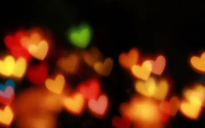Topli žuti i crveni bokeh svjetlosni efekti na tamnoj pozadini stvaraju blagdanski ugođaj.