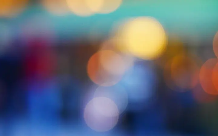 Raznobojni bokeh krugovi na tamnoj pozadini stvaraju efekt dubine i prostranosti.