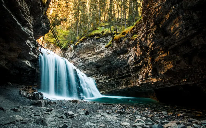 Vodopad okružen kanjonom i stijenama s prirodnim zemljanim tonovima u prizoru.