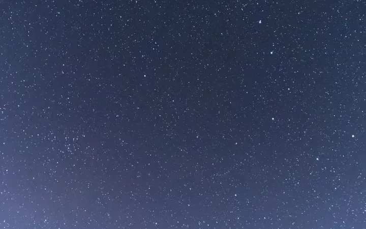 Blagi prijelaz boja u noćnom nebu s vidljivim zviježđima i galaksijama u nježnim nijansama.