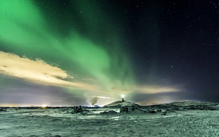 Hladno zimsko nebo osvijetljeno zelenim svjetlima aurora borealisa nad zaleđenim krajolikom.