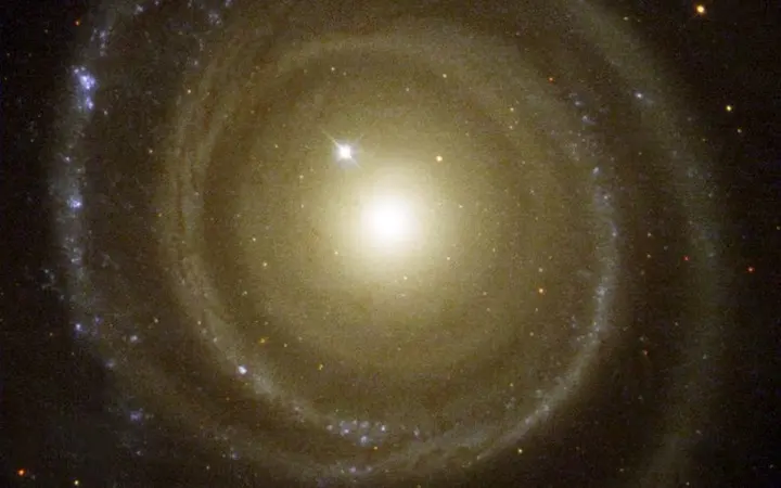 Svijetla spiralna galaksija s neobičnim smjerom rotacije prikazana na tamnom svemirskom nebu.