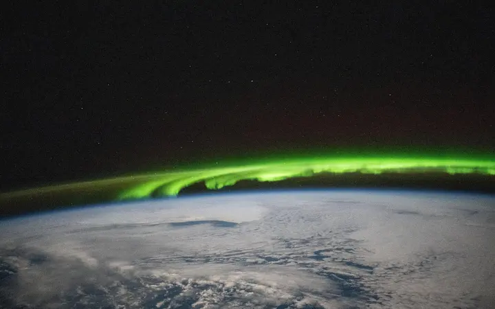 Jarka zelena aurora borealis teče iznad Zemljine površine u noćnom okruženju, viđena iz svemira s visine 269 milja.