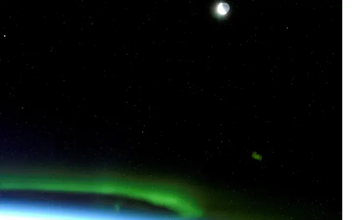 Aurora borealis prikazana u zelenim nijansama koje obasjavaju tamno nebo tijekom noći, snimljena iz svemira.