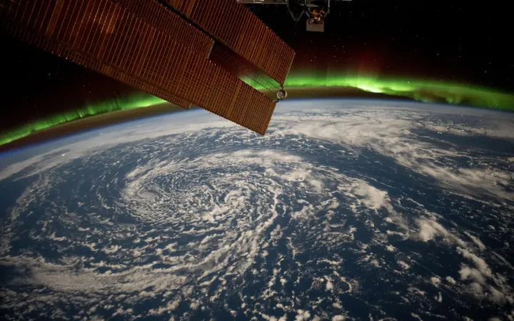 Oblaci se kovitlaju iznad zaljeva Aljaske dok zelena aurora borealis osvjetljava horizont Zemlje iz svemira.