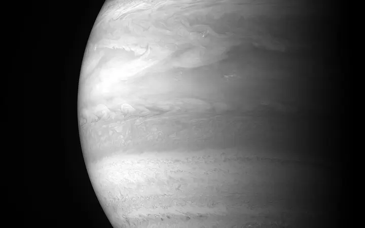 Svijetli i prozirni oblaci visoko u atmosferi Jupitera s plavim i bijelim tonovima pod jakim svjetlom.