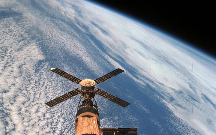 Pogled na klaster svemirske stanice Skylab iz orbite Zemlje s plavom i bijelom pozadinom planeta.
