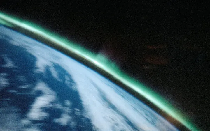 Zelenkasti valovi aurore Australis vijugaju se u tamnoj atmosferi s oštrim svjetlosnim vrhovima.